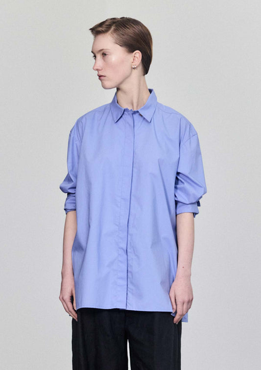 Model wearing Leophil's relaxed Women's cotton shirt in light blue with pushed up sleeves and soft collar