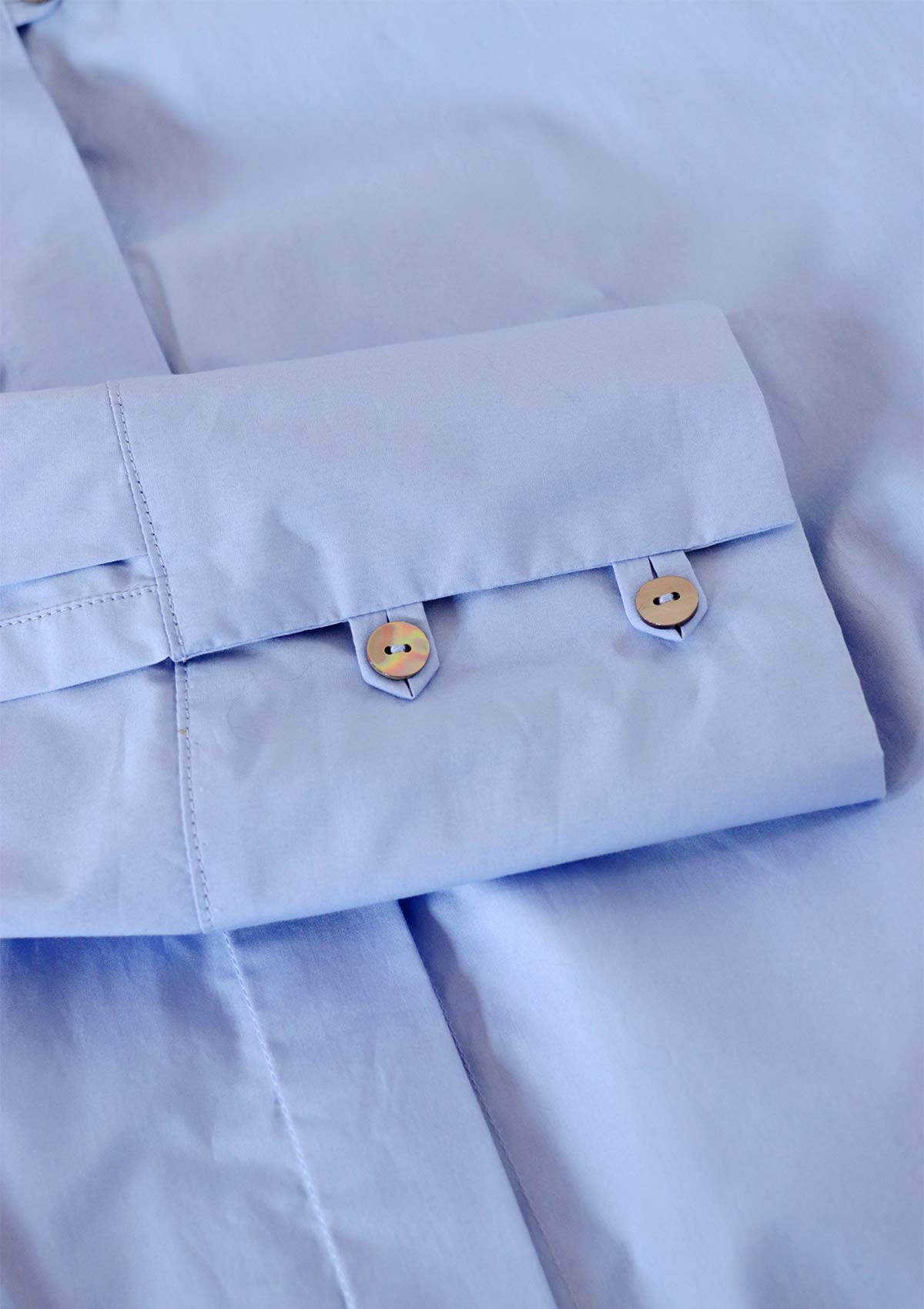 Cuff detail of Leophil's relaxed Women's cotton shirt in light blue with loop closure and shell buttons