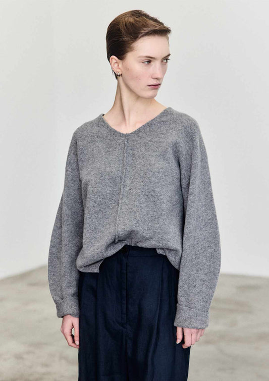 Model wearing the Quinn V-neck Merino sweater in grey styled with a tucked waist and rolled up sleeves