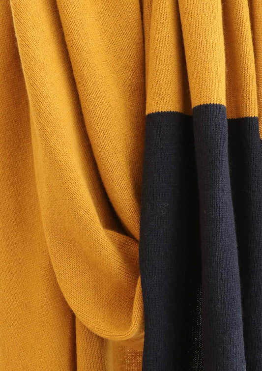 Close up of ADA fine knit scarf in mustard yellow and a navy striped end. Knitted from a cashmere blend yarn for a beautiful drape